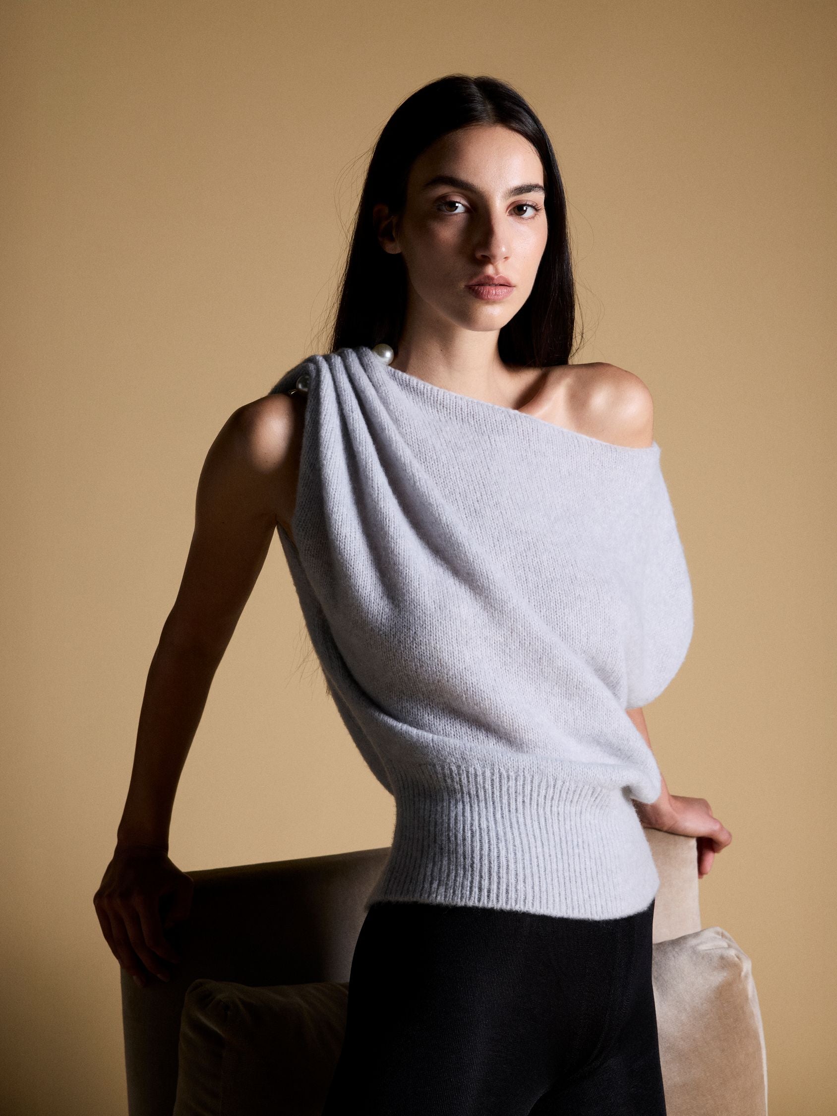 Soft knit asymmetric shoulder top with pearl accessory.
